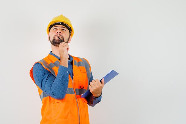 Joven constructor con portapapeles y lápiz en camisa