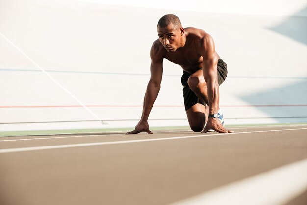 Joven corredor africano comenzando y preparándose para correr