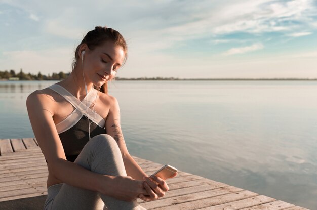 Joven dama deportiva en la playa escuchando música con auriculares.