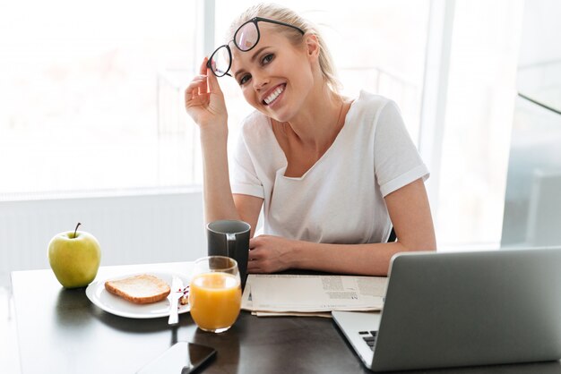 Joven dama feliz quitarse las gafas y mirando en la cocina