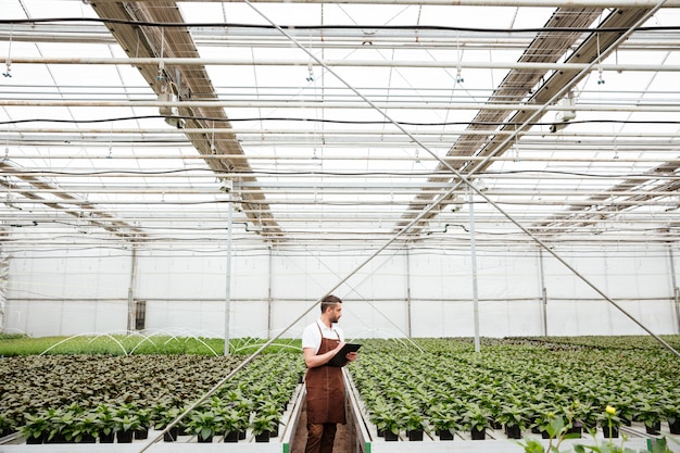 Joven en delantal trabajando con plantas en zonas verdes