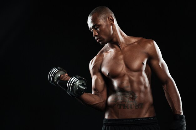 Un joven deportista afroamericano medio desnudo levantando pesas