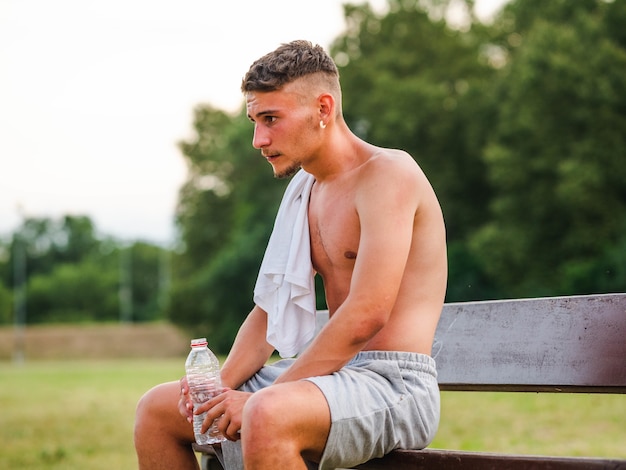 Joven deportista atractivo beber agua después del entrenamiento - concepto de deporte