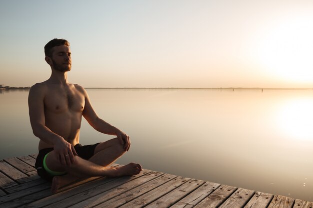 Joven deportista concentrado hacer ejercicios de meditación y yoga