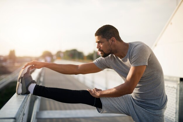 Joven deportista corredor estirando las piernas y calentando para correr