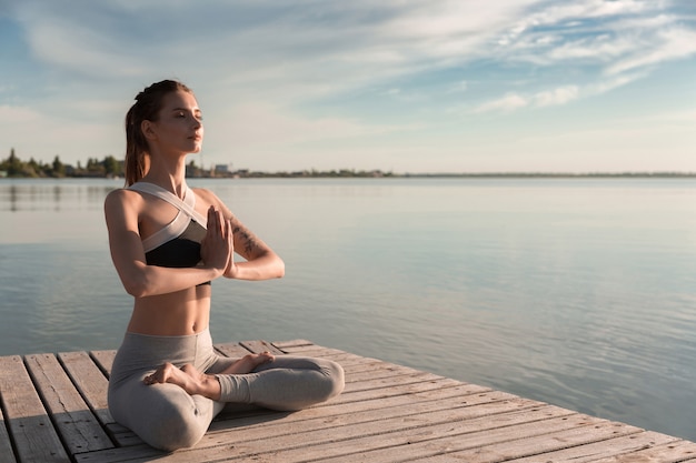 Joven deportista en la playa hacer ejercicios de meditación.