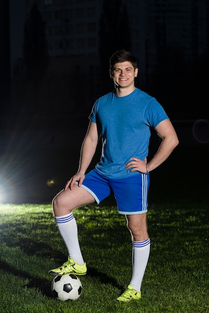 Joven deportista posando cerca de balón de fútbol