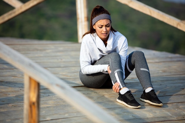 Foto gratuita joven deportista que experimenta dolor en la pierna mientras entrena deportes en la naturaleza