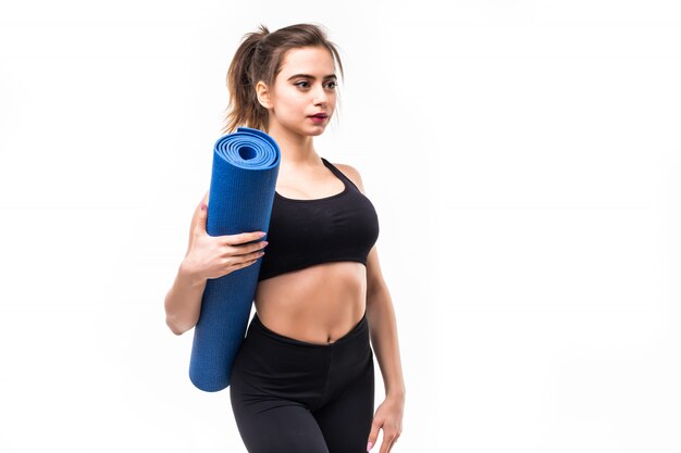 Joven deportista en ropa deportiva negra practicando yoga en una estera.