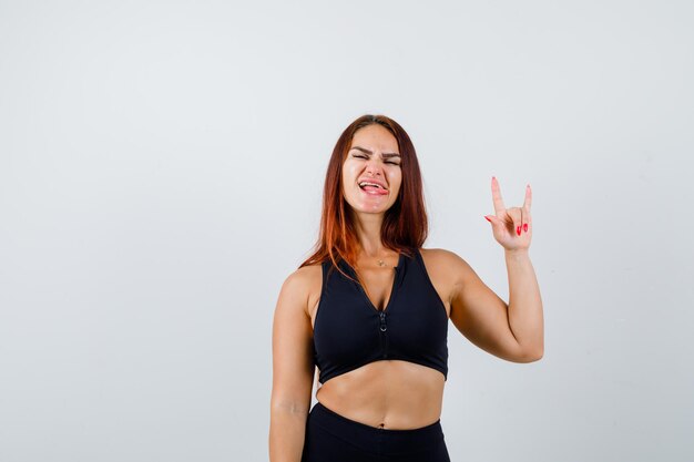 Joven deportiva con cabello largo mostrando gesto de rock