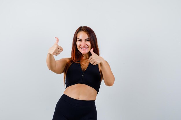 Joven deportiva con cabello largo mostrando los pulgares para arriba