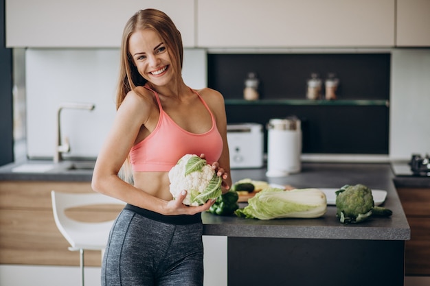 Foto gratuita joven deportiva con coliflor en la cocina