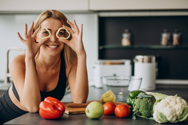 Joven deportiva con pimienta en la cocina