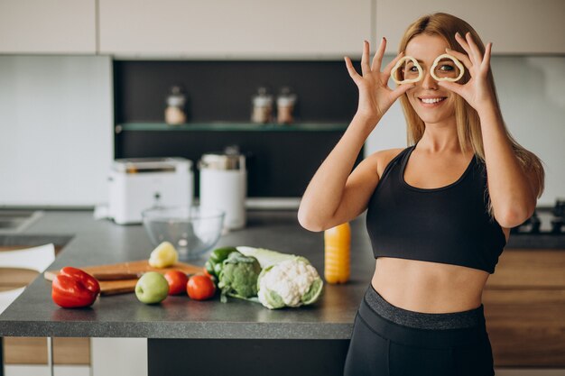 Joven deportiva con pimienta en la cocina