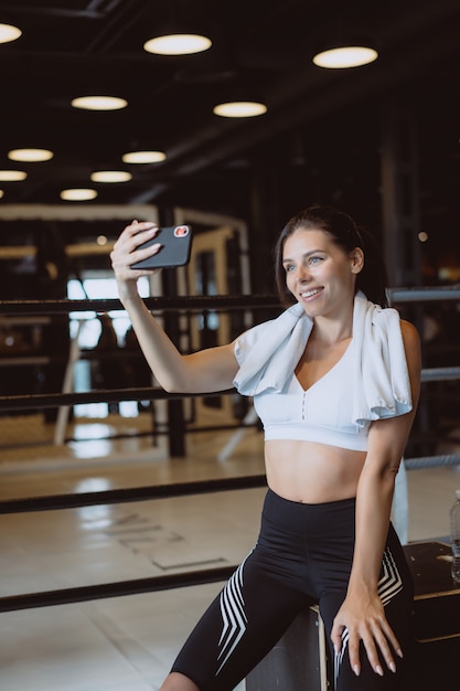 Joven deportiva tomando un selfie con teléfono móvil en el gimnasio