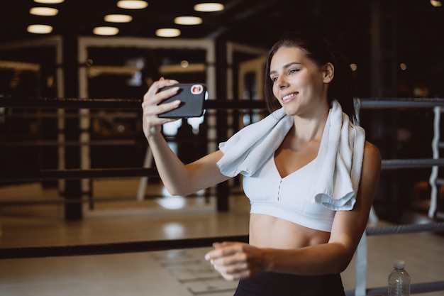 Foto gratuita joven deportiva tomando un selfie con teléfono móvil para redes sociales en el gimnasio.