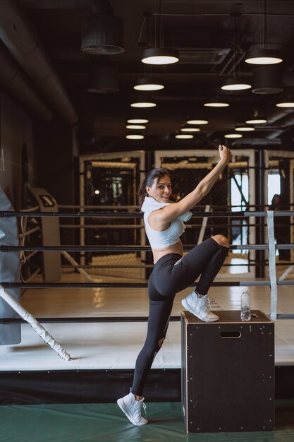 Joven deportiva tomando un selfie con teléfono móvil para redes sociales en el gimnasio.