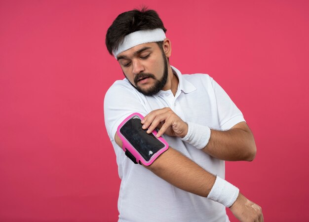 Joven deportivo vistiendo diadema y muñequera con brazalete de teléfono