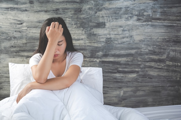 Foto gratuita joven está deprimida en una cama blanca