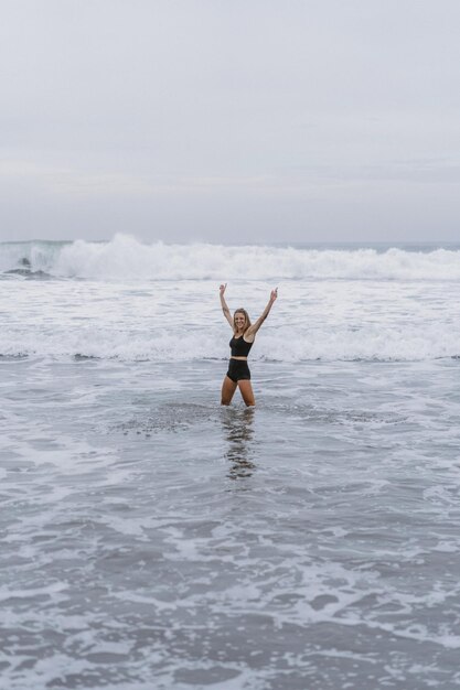 Una joven descalza con un cuerpo esbelto corre sobre las olas del mar junto a la piscina de agua para mantenerse en forma y quemar grasa. Fondo de playa con cielo azul. Fitness para mujeres, jogging, actividades deportivas en una familia de verano.