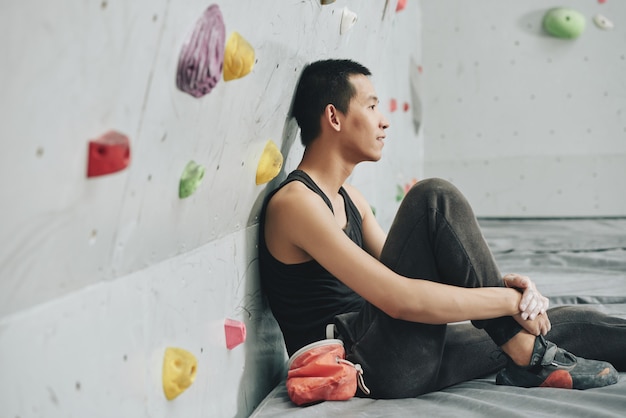 Joven descansando en el gimnasio de escalada