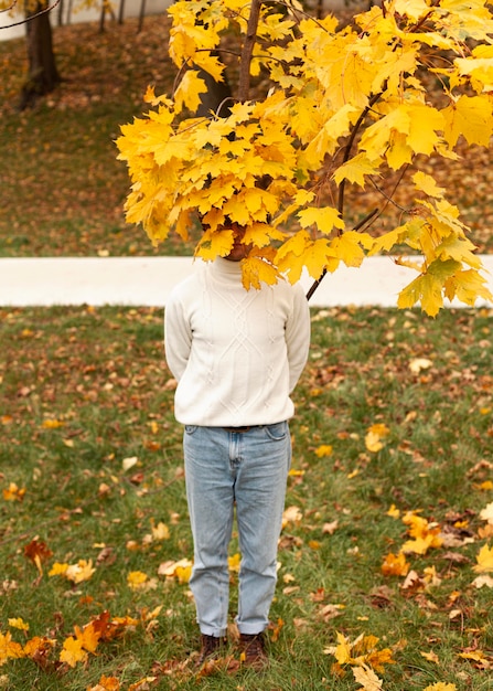 Joven detrás de hojas de otoño