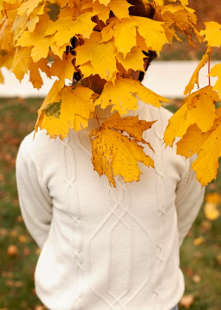 Joven detrás de hojas de otoño