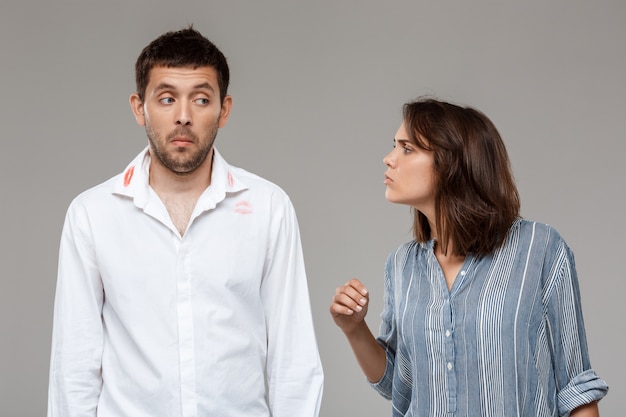 Joven discutiendo, enojado con marido borracho sobre pared gris