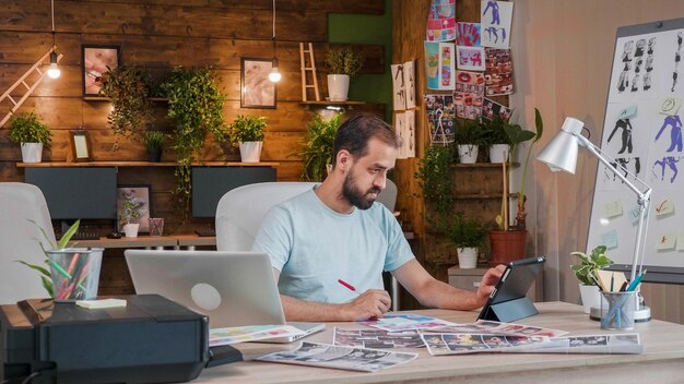 Joven diseñador trabajando en una tableta y tomando notas. Oficina inteligente y creativa