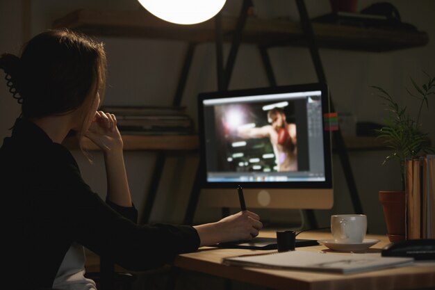 Joven diseñadora concentrada en la noche usando la computadora