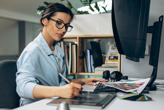 Foto gratuita joven diseñadora digital que trabaja en tableta y computadora