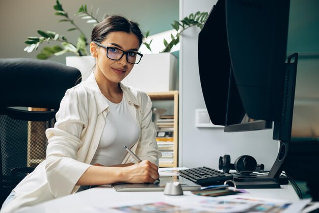 Joven diseñadora digital que trabaja en tableta y computadora