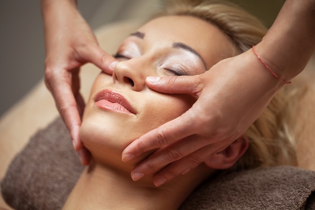 Joven disfruta de un masaje facial en spa