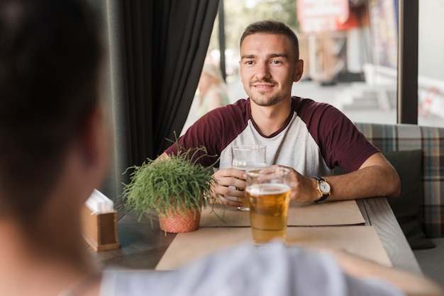 Foto gratuita joven disfrutando de una bebida con su amigo