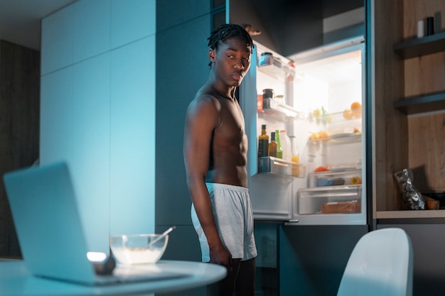 Foto gratuita joven disfrutando de un bocadillo en casa en medio de la noche