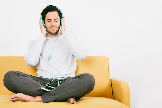 Joven disfrutando de la música en el sofá