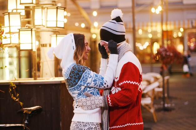 Una joven se divierte con su novio y su sombrero mientras camina por el mercado navideño.