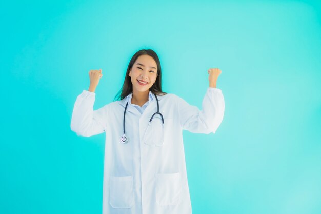 Joven doctora asiática con estetoscopio haciendo expresión feliz