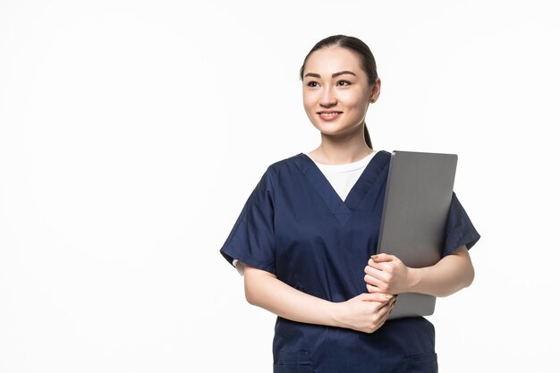 Joven doctora asiática sosteniendo ordenador portátil, con estetoscopio, aislado en la pared blanca