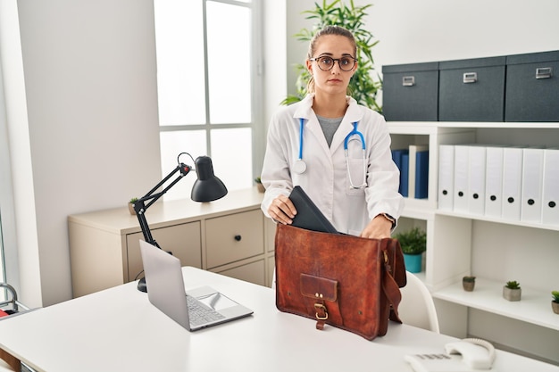 Joven doctora en la clínica escéptica y nerviosa frunciendo el ceño molesta por el problema de una persona negativa