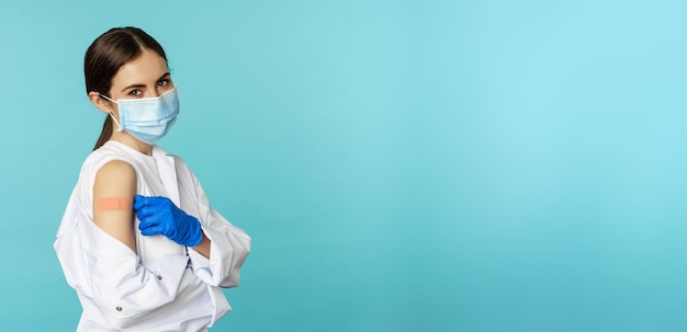 Foto gratuita joven doctora enfermera con mascarilla médica y uniforme de hospital mostrando los pulgares hacia arriba después de recibir