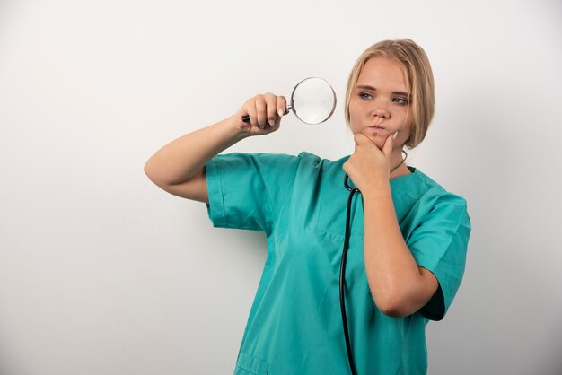 Joven doctora con estetoscopio y lupa.