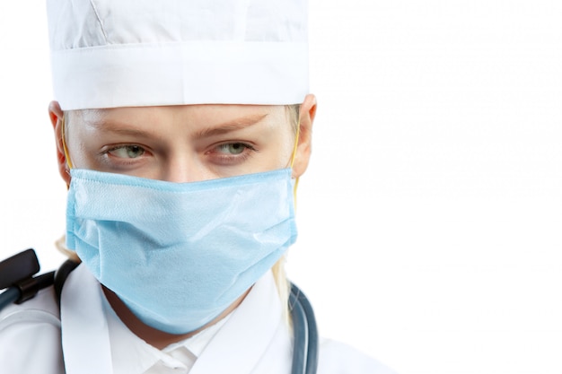 Joven doctora con estetoscopio y mascarilla aislado en blanco