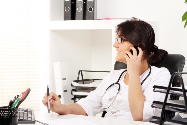 Joven doctora hablando por teléfono