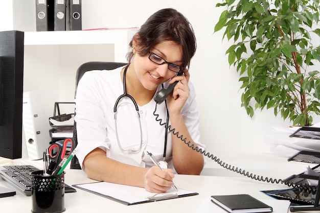 Joven doctora hablando por teléfono