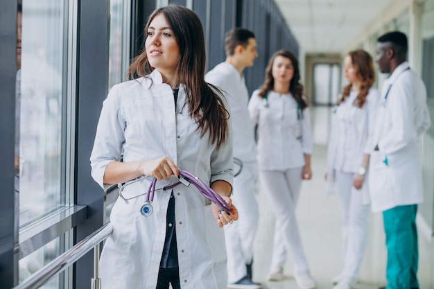 Joven doctora mirando la ventana desde el pasillo del hospital