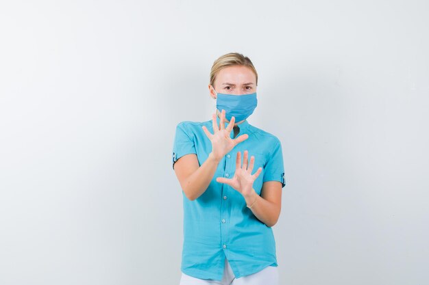 Joven doctora mostrando palmas en gesto de rendición en uniforme médico