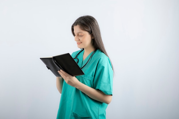 joven doctora de pie con cuaderno y lápiz.