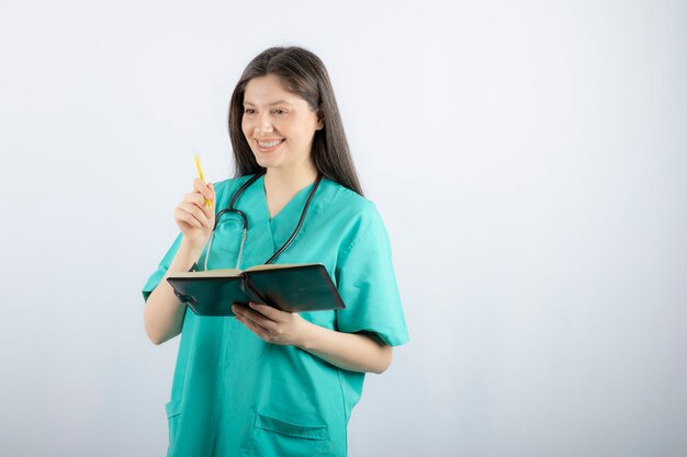 joven doctora de pie con cuaderno y lápiz.