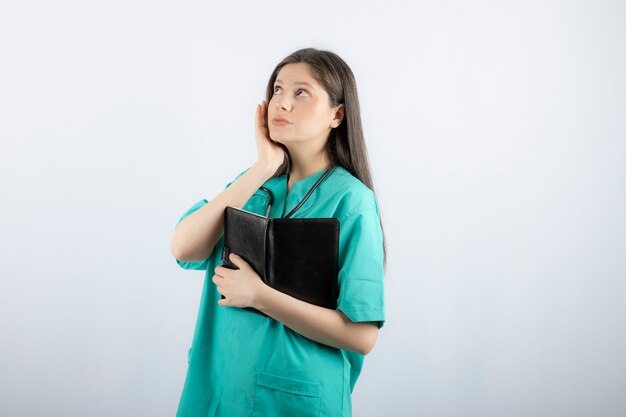 joven doctora de pie con cuaderno y lápiz.